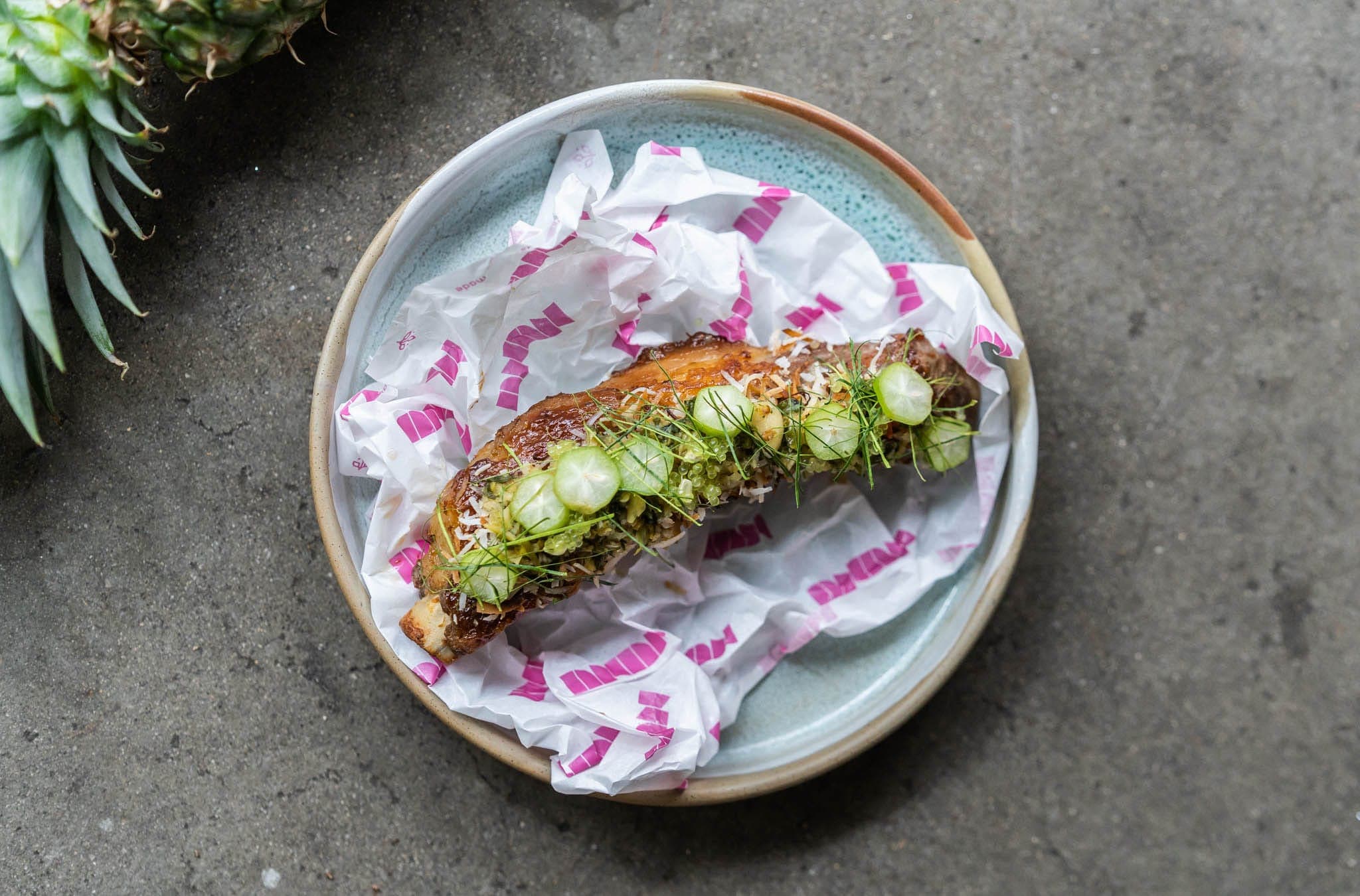 Glazed pork belly with finger lime and coconut, served in branded paper