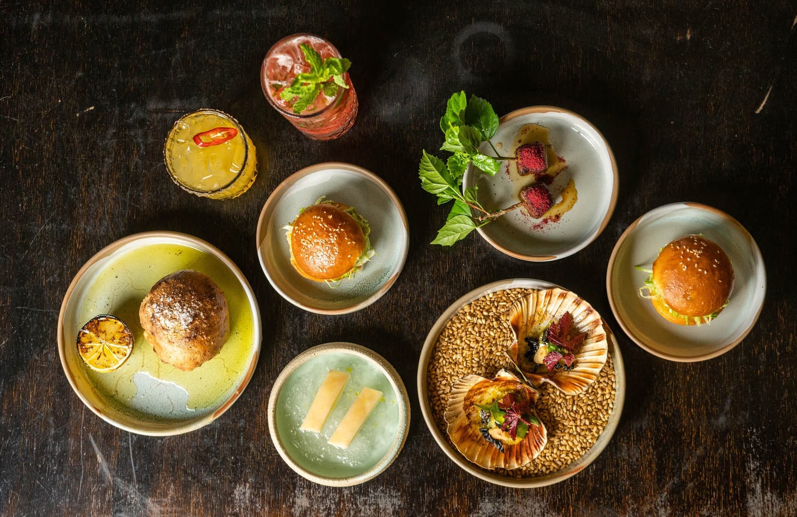 Overhead spread of Nu Nu plates and cocktails on a dark timber table